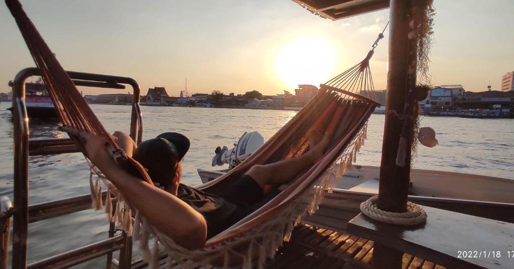 un hombre tendido en una hamaca en un barco en Sabai Sabai Liveaboard Bangkok en Bangkok