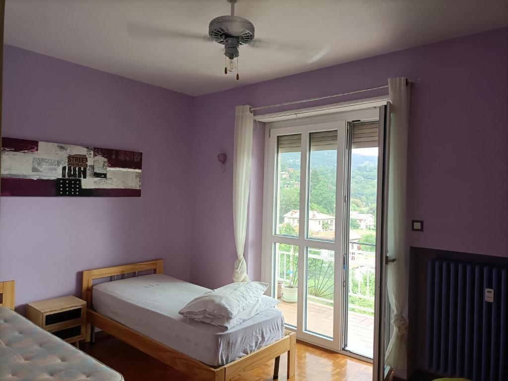a bedroom with two beds and a large window at TORRE PELLICE Camera In Bilocale con bagno in comune in Torre Pellice