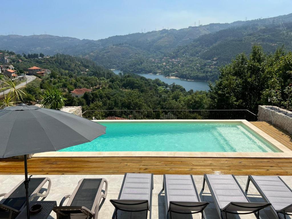 a swimming pool with chairs and an umbrella at Gerês - Refúgio das Laranjeiras in Geres