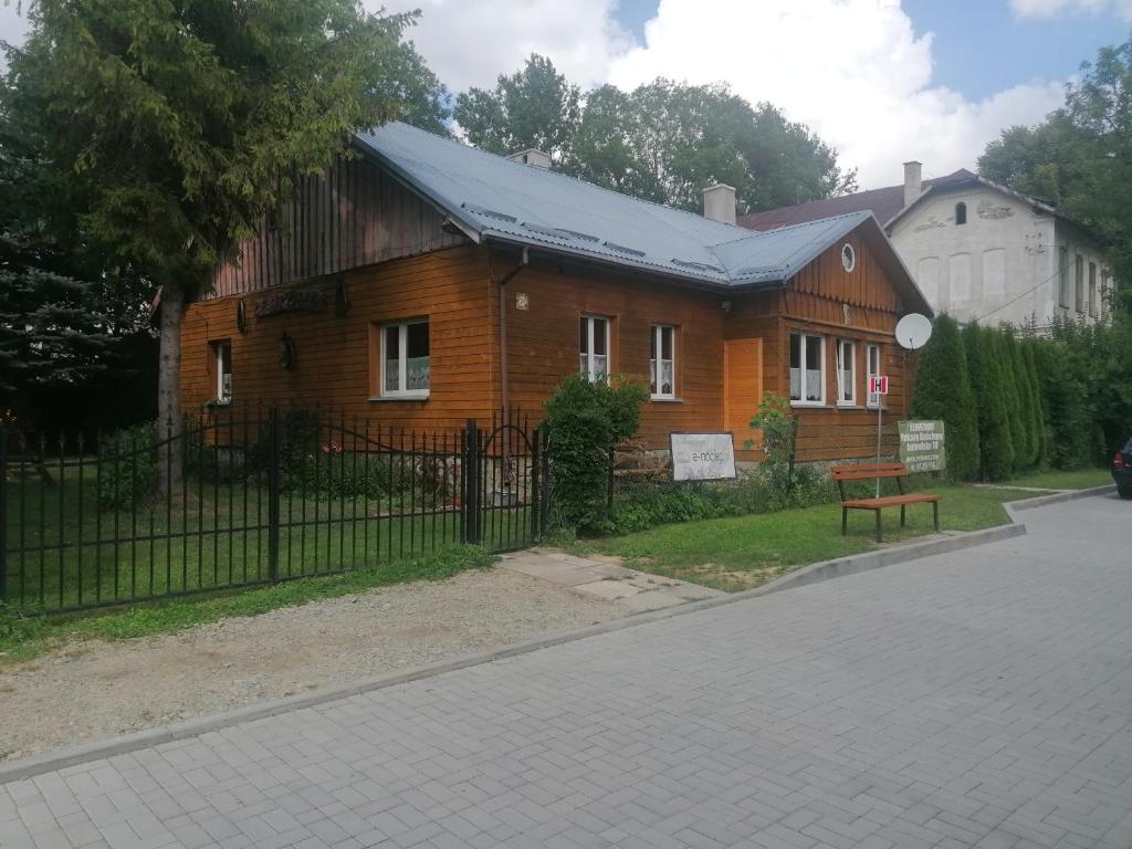 uma casa de madeira com uma cerca em frente em Łemkowo Pokoje Gościnne em Lutowiska