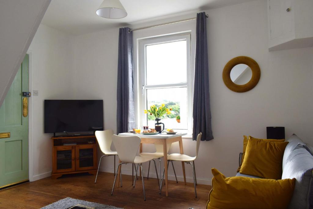 a living room with a table and chairs and a window at Cockleshell Cottage in Falmouth