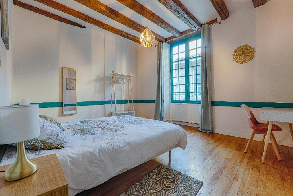 Schlafzimmer mit einem Bett, einem Tisch und einem Fenster in der Unterkunft La Ballerine - Baby foot - Centre historique in Romans-sur-Isère