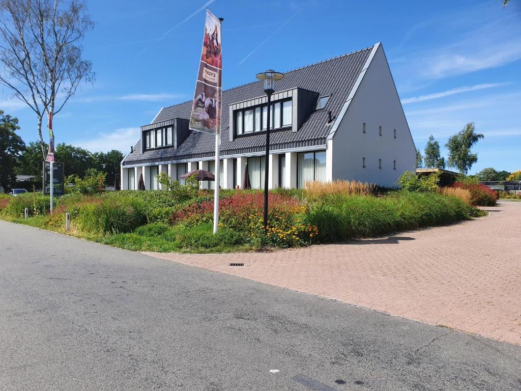 un edificio con una bandera al lado de una carretera en Hotel de Boshoek en Voorthuizen
