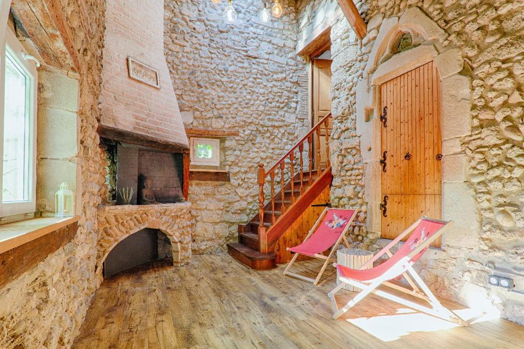 Zimmer mit 2 Stühlen und einem Steinkamin in der Unterkunft La Ballerine - Baby foot - Centre historique in Romans-sur-Isère