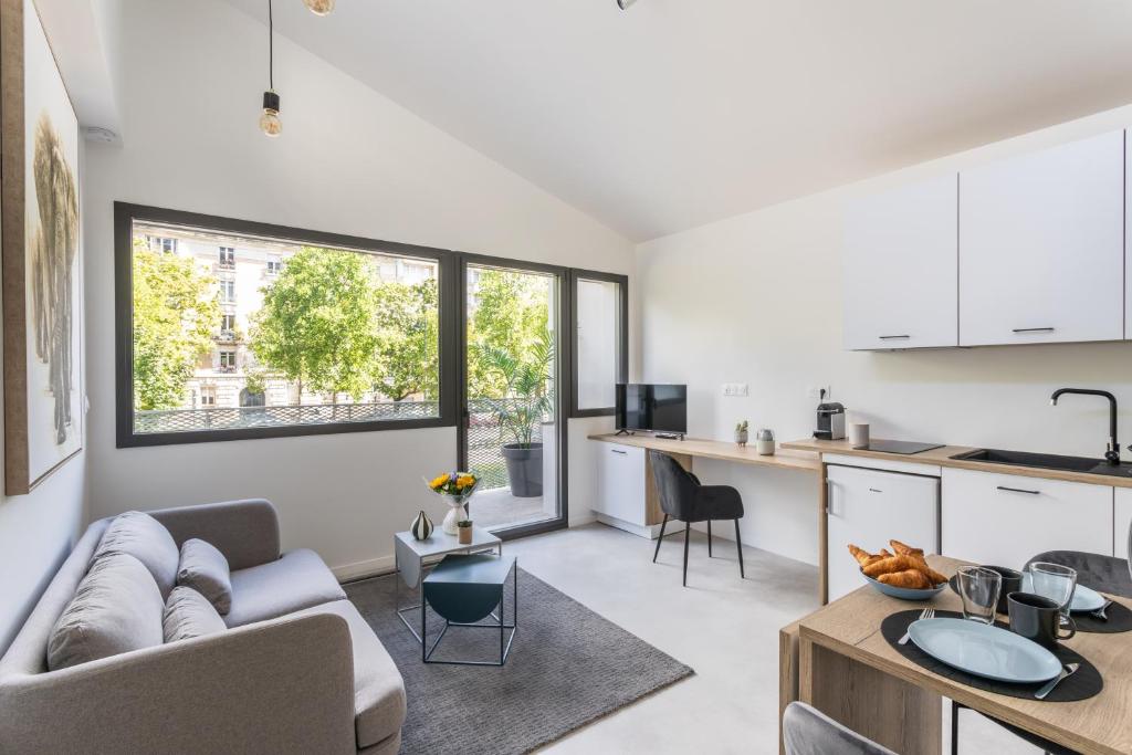 cocina y sala de estar con sofá y mesa en Residence Iles Bretonnes, en Rennes