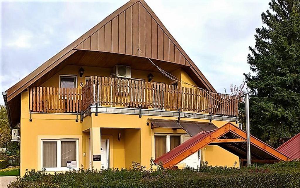 une maison jaune avec un balcon et un escalier dans l'établissement Balassa Családi Apartman, à Vonyarcvashegy