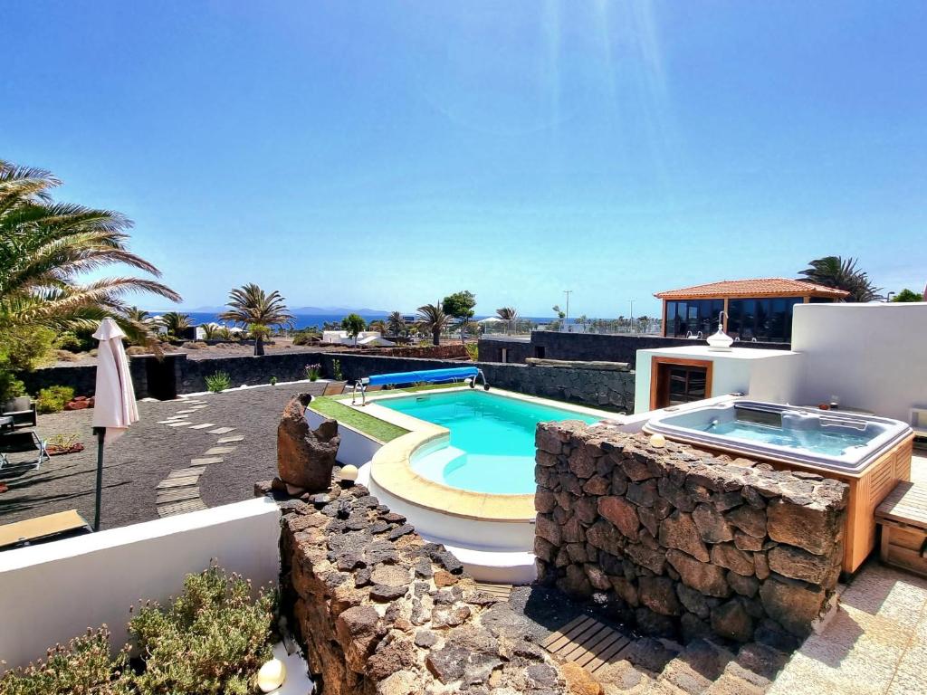 a villa with a swimming pool and a stone wall at Casa Olgita in Playa Blanca