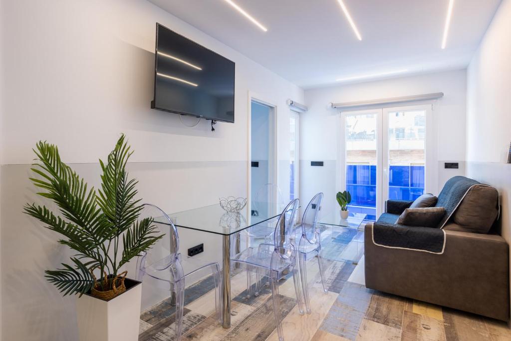 a living room with a glass table and a tv on the wall at MUNDOBOOKING Centro Levante in Benidorm