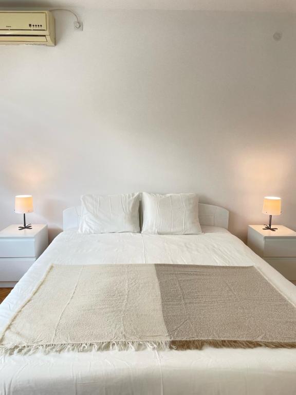 une chambre avec un grand lit blanc avec deux lampes dans l'établissement The Blue Velvet Apartment, à Belgrade