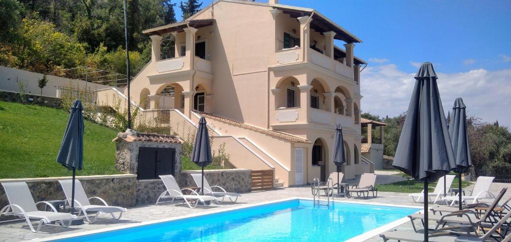 a villa with a swimming pool and chairs and umbrellas at BOSCO VERDE Corfu Apartments in Gouvia