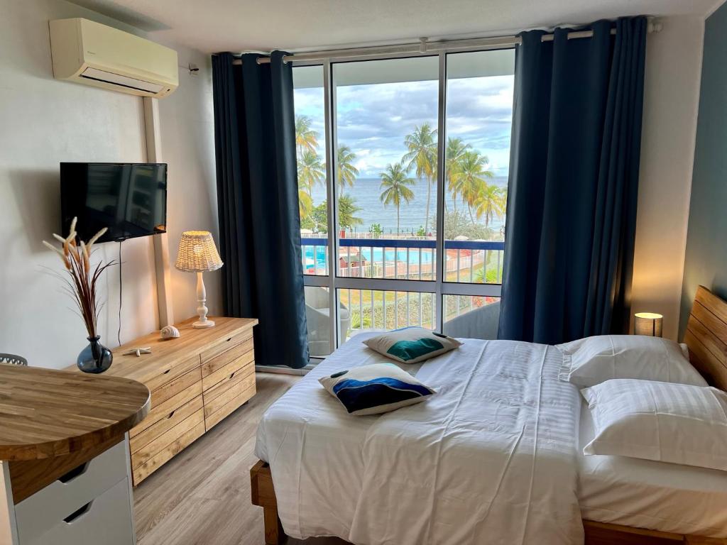 une chambre avec un lit avec vue sur l'océan dans l'établissement Soleiade Le Gosier - Accès Plage, au Gosier