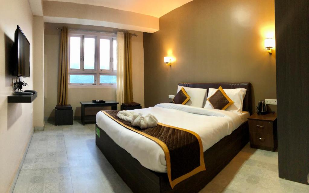 um quarto de hotel com uma cama grande e uma janela em ALL SEASONS HOTEL em Gangtok