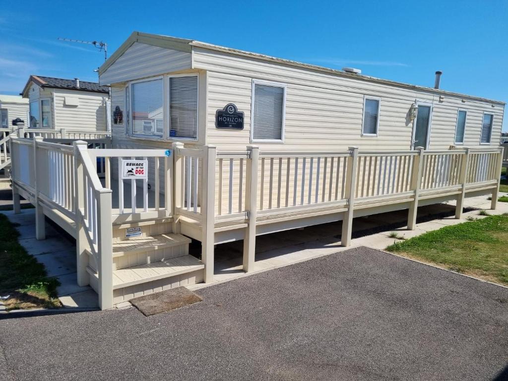a mobile home with a porch and a fence at PG49 8 BERTH PET FRIENDLY CARAVAN GOLDEN PALM in Chapel Saint Leonards