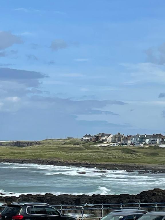 dois carros estacionados ao lado de um corpo de água em Atlantic Port Retreat em Portstewart