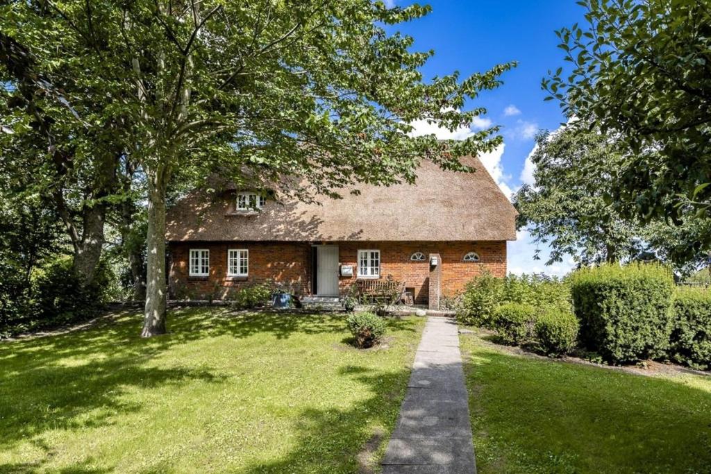 an old brick house with a grass yard at Ferienhaus Katzhörn in Emmelsbüll-Horsbüll