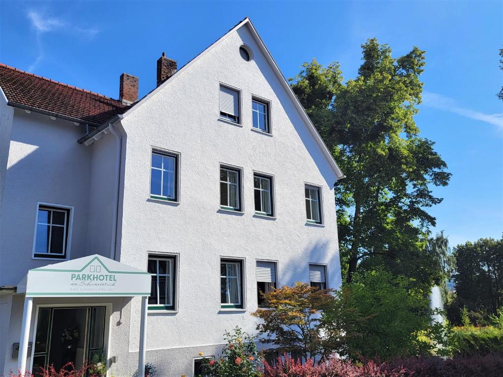 ein weißes Haus mit einem Schild davor in der Unterkunft Parkhotel Am Schwanenteich in Bad Sooden-Allendorf