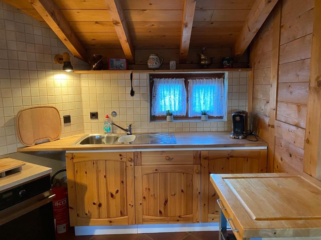 cocina con armarios de madera, fregadero y ventana en Klein Kattult, en Windeck