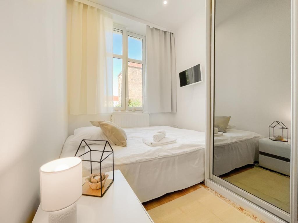 biały pokój z lustrem i łóżkiem w obiekcie COCO Apartments Gdańsk Centrum Górka w Gdańsku