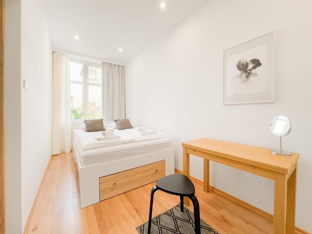 a white bedroom with a bed and a desk at COCO Apartments Gdańsk Centrum Górka in Gdańsk