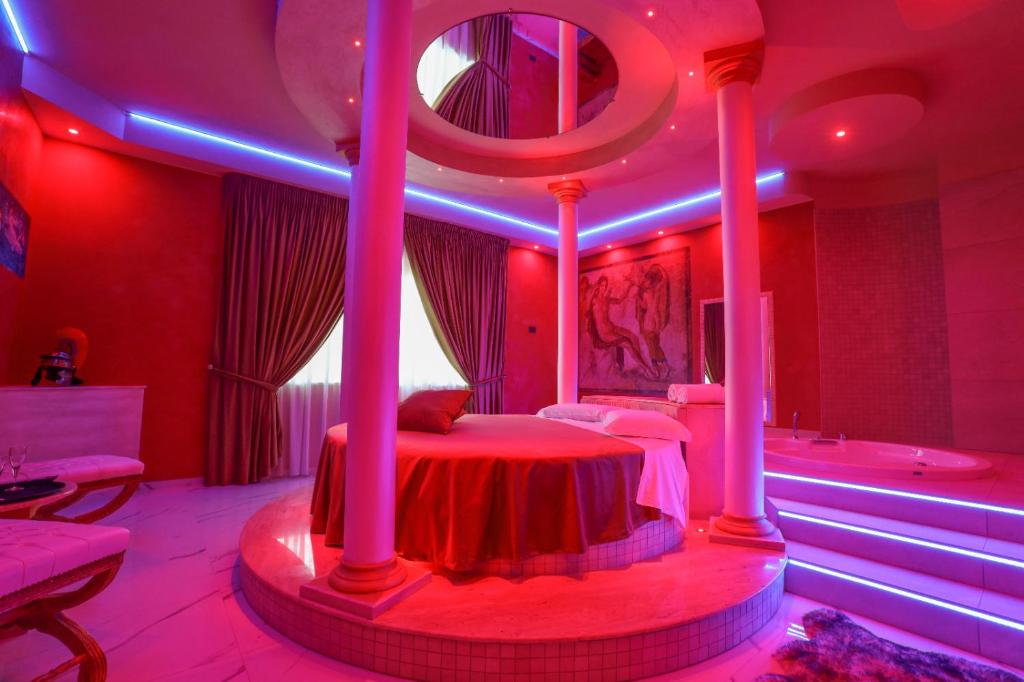 Alcova Suite&Relax في إبولي: غرفة نوم مع سرير وحوض استحمام مع أضواء أرجوانية