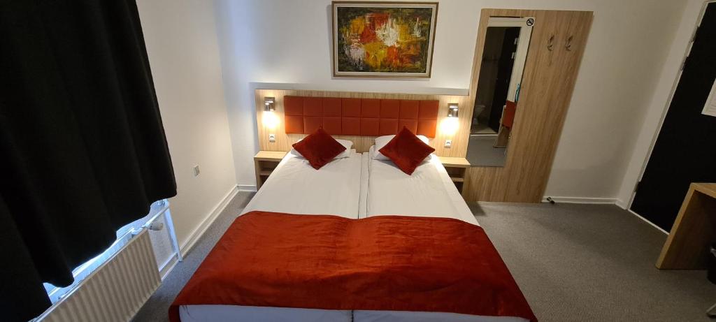 a bedroom with a large bed with red and white sheets at Prinsen Hotel in Aalborg