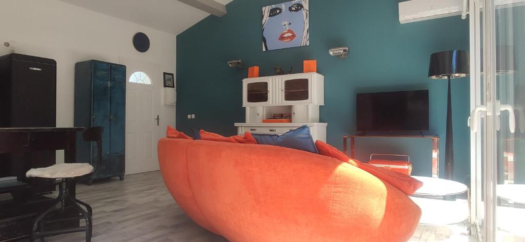 een woonkamer met een oranje bank met kussens bij Rose BB maison de charme in Les Lecques