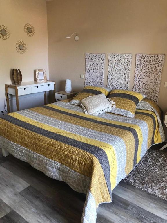 - une chambre avec un grand lit et une couverture jaune et bleue dans l'établissement lagalerne, à Neuville-du-Poitou