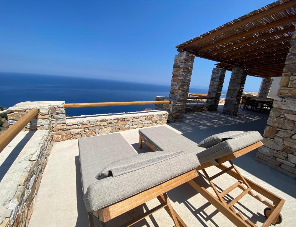 een patio met 2 stoelen en een tafel op een dak bij Blue Calm Luxury Villa in Sifnos in Artemonas