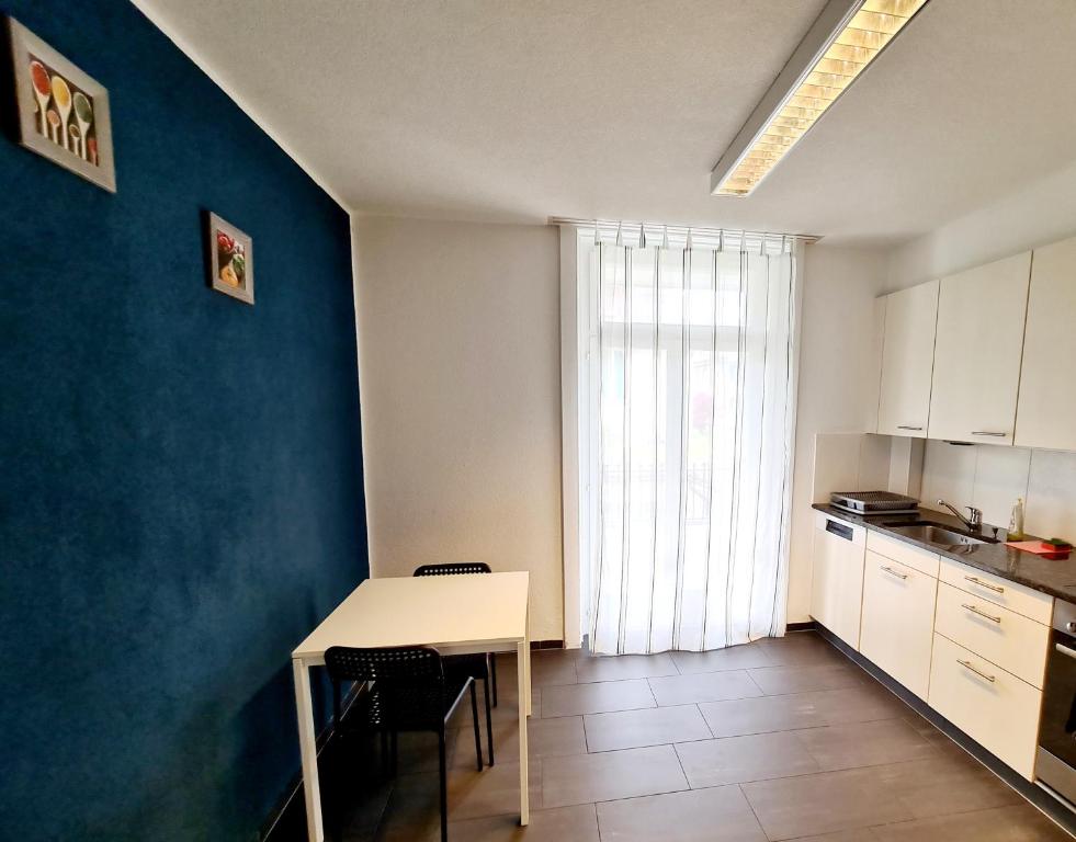 cocina con mesa blanca y pared azul en Swiss Holidays Apartment Rosenstrasse 10, en Interlaken