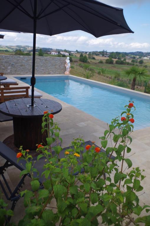 uma mesa com um guarda-sol ao lado de uma piscina em Maison Elizondoa em Masparraute