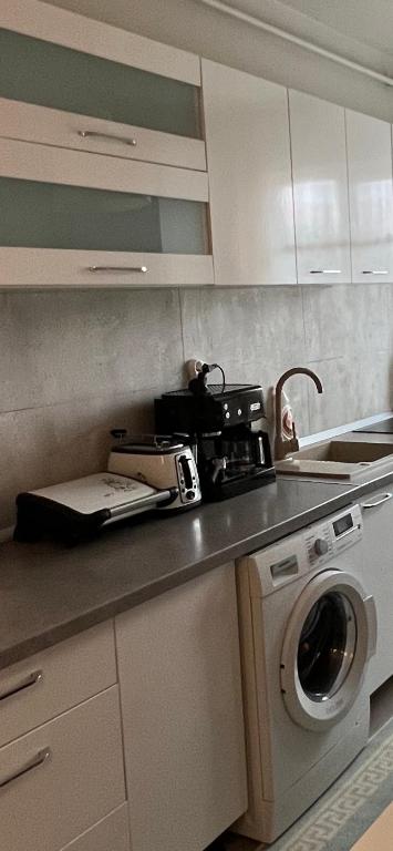 a kitchen with a sink and a washing machine at Apartament spatios, mobilat si utilat complet in Floreşti