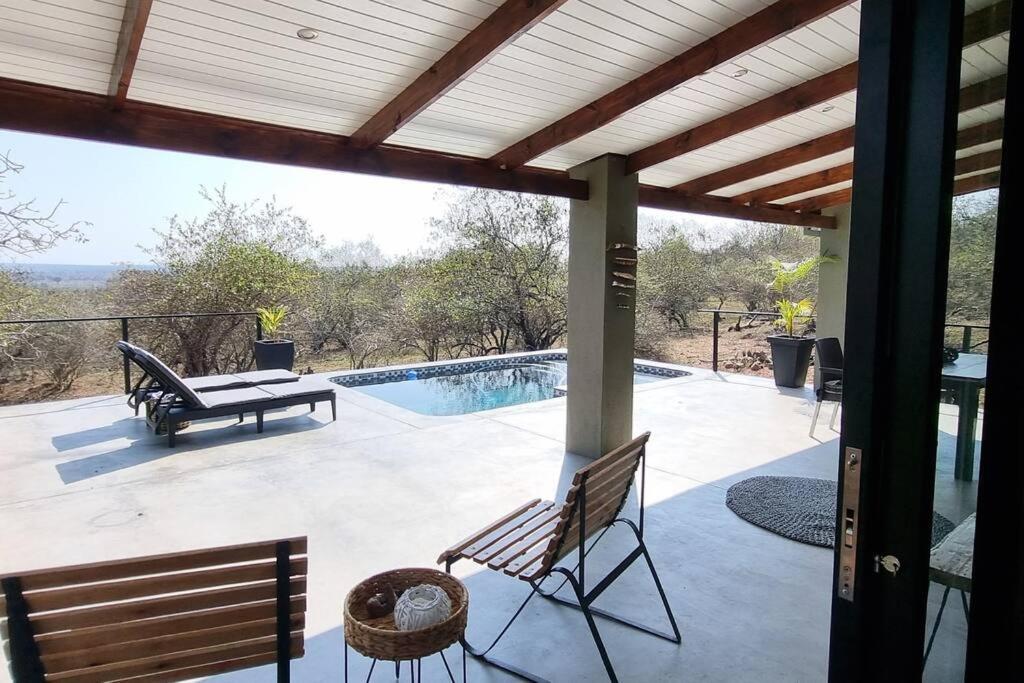 een patio met een tafel en stoelen en een zwembad bij Palahala in Marloth Park