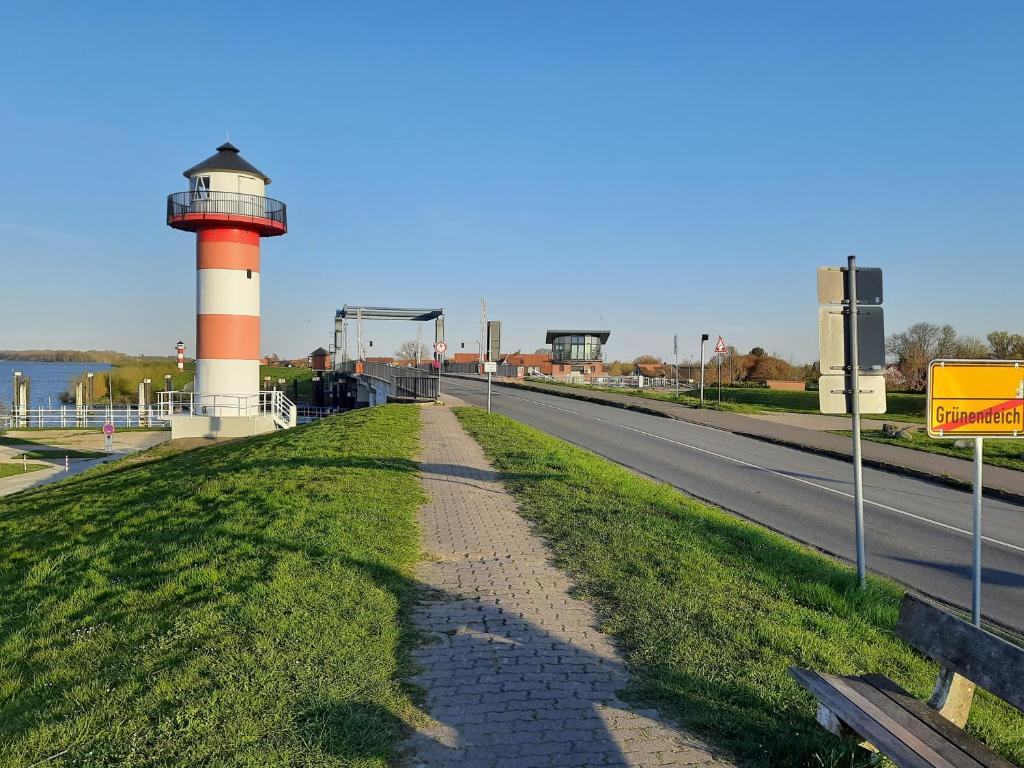 eine Straße mit einem Leuchtturm am Straßenrand in der Unterkunft Auszeit am Fähranleger in Grünendeich