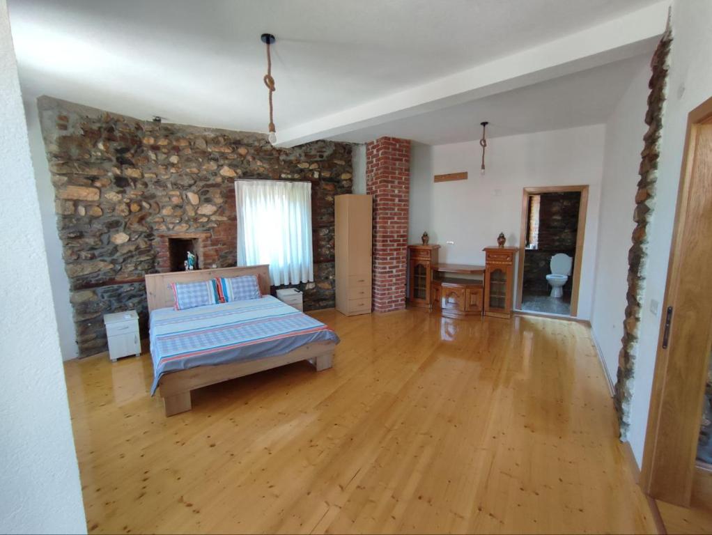 a bedroom with a bed and a stone wall at House of Poposka Kuka in Bitola