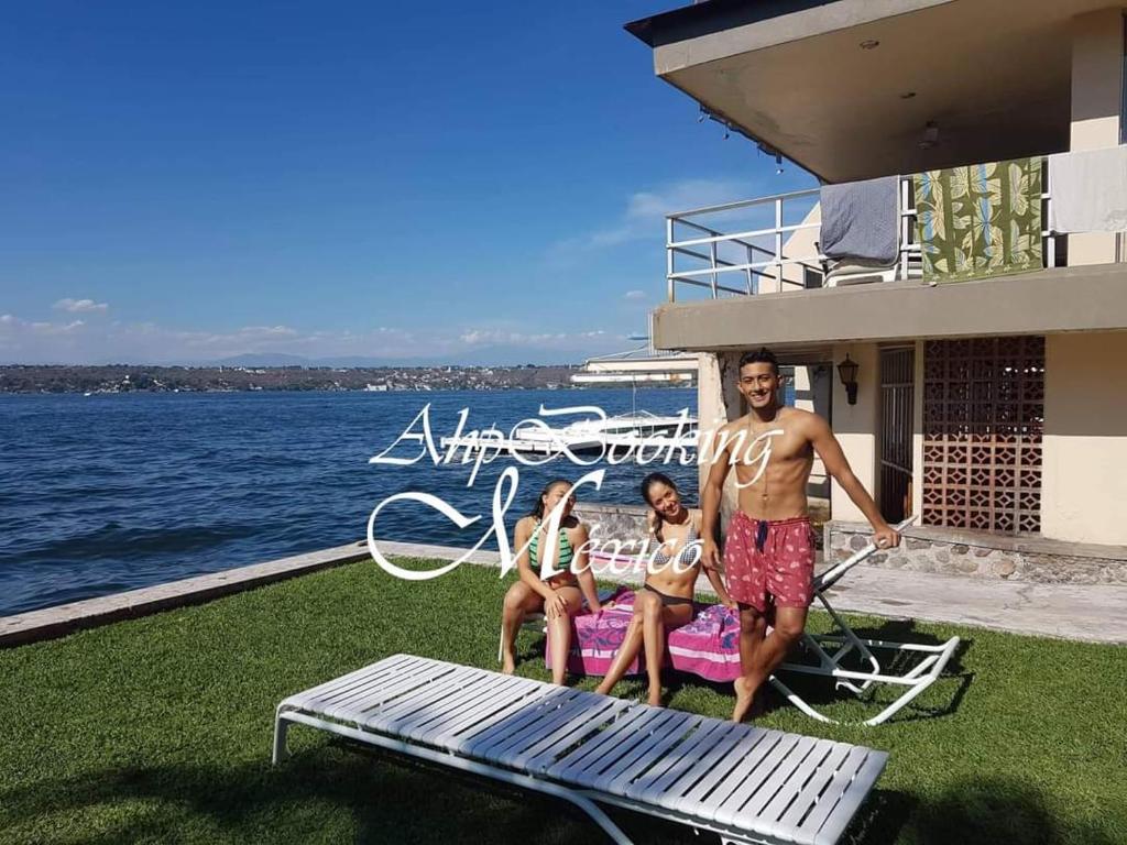 un hombre y dos chicas están sentados en un diván en Bella casa a la orilla del lago & estacionamiento en Tequesquitengo