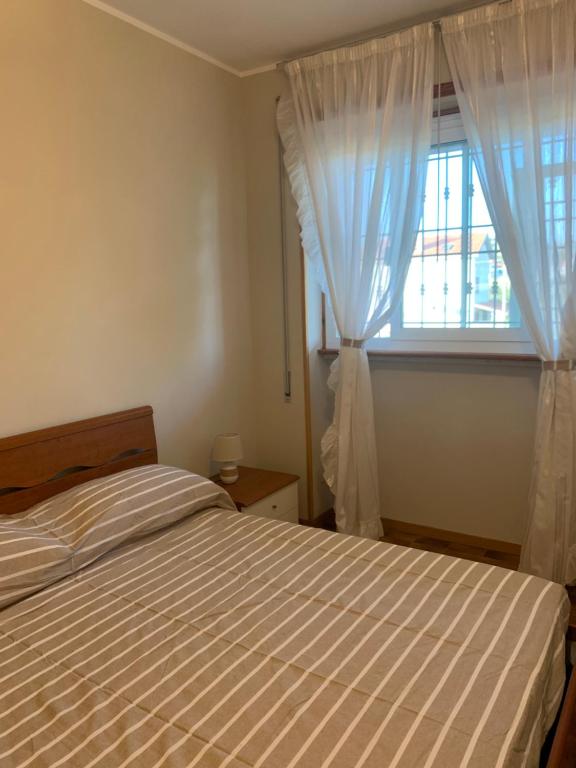 a bedroom with a bed and a window with curtains at Sunset Apartment in Santa Marinella