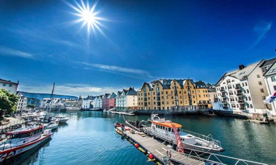 a group of boats docked in a river with buildings at Ålesund Apartment with free parking in Ålesund