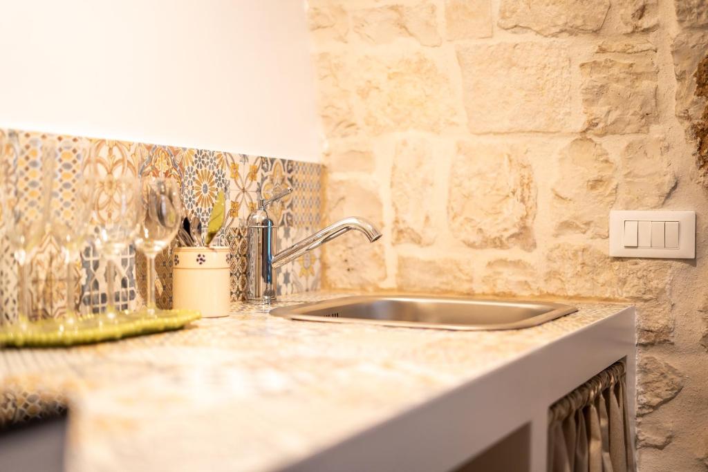 - un comptoir de cuisine avec un évier et un mur en pierre dans l'établissement Il trullo del Guelfo, à Alberobello