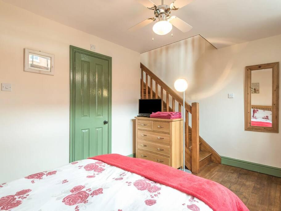 a bedroom with a bed with a green door and a dresser at Stable Cottage, Bishops Castle in Bishops Castle