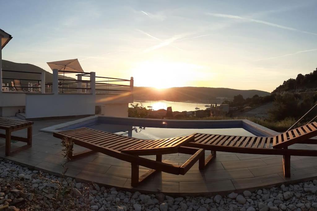 a patio with two benches and a swimming pool at Vis - luxury holiday villa with swimming pool in Vis