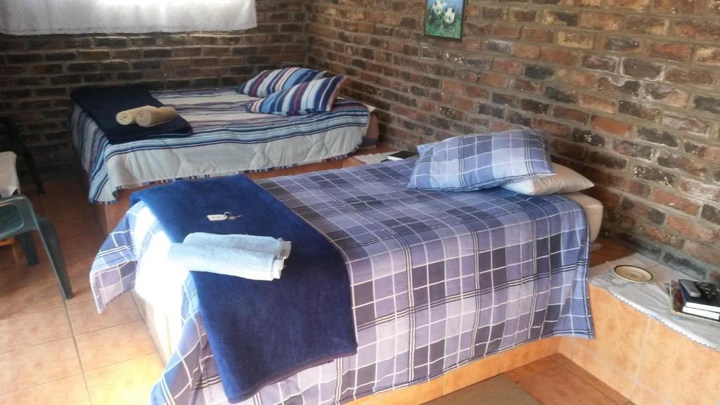 two beds in a room with a brick wall at Onze Rust Guest House and caravanpark in Colesberg