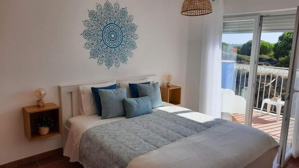 a bedroom with a bed with blue pillows and a balcony at Beach House - Casa de Férias MONTE CLÉRIGO in Aljezur