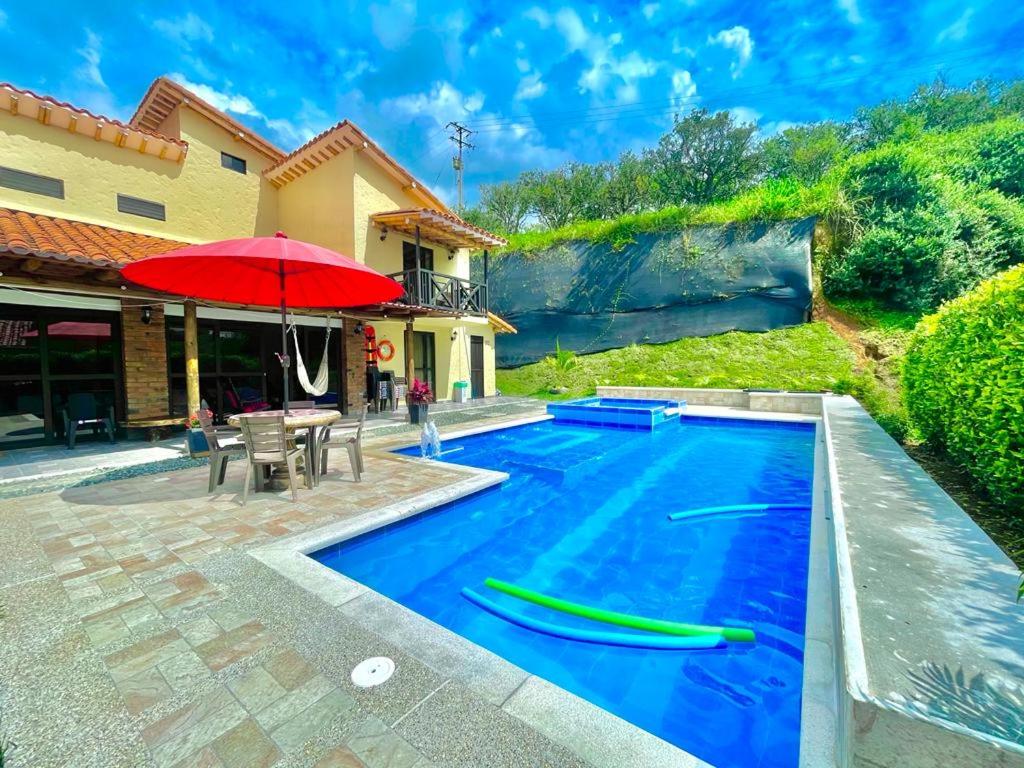 una piscina con ombrellone rosso accanto a una casa di Villa Lupalú - Fincas Panaca- a El Laurel