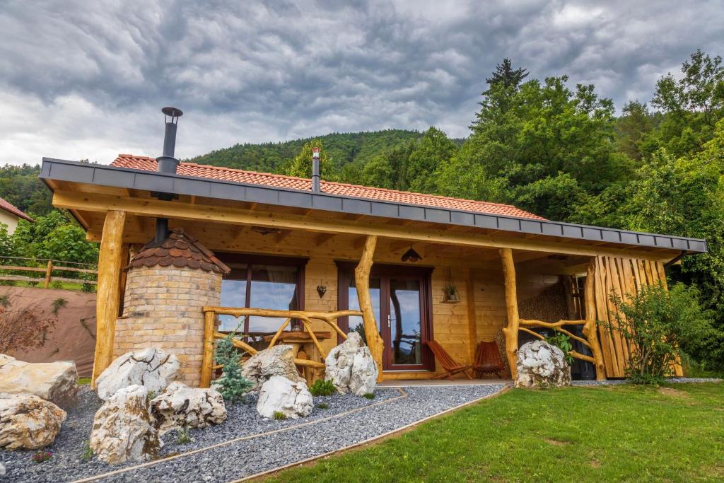 a log cabin with a stone fireplace in the yard at Lake Cottage - Koča ob jezeru in Nazarje