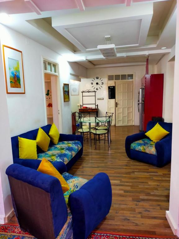 a living room with blue couches and yellow pillows at Casa Tligui in Asilah