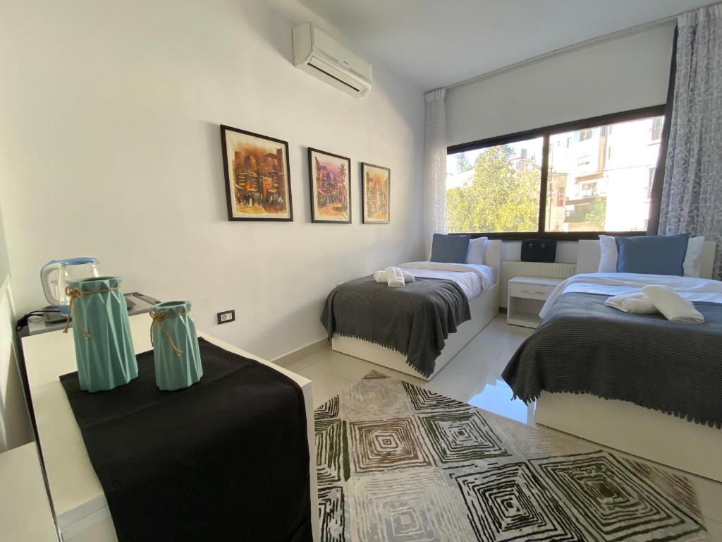a bedroom with two beds and a table and a window at Lemon Tree Residence in Amman