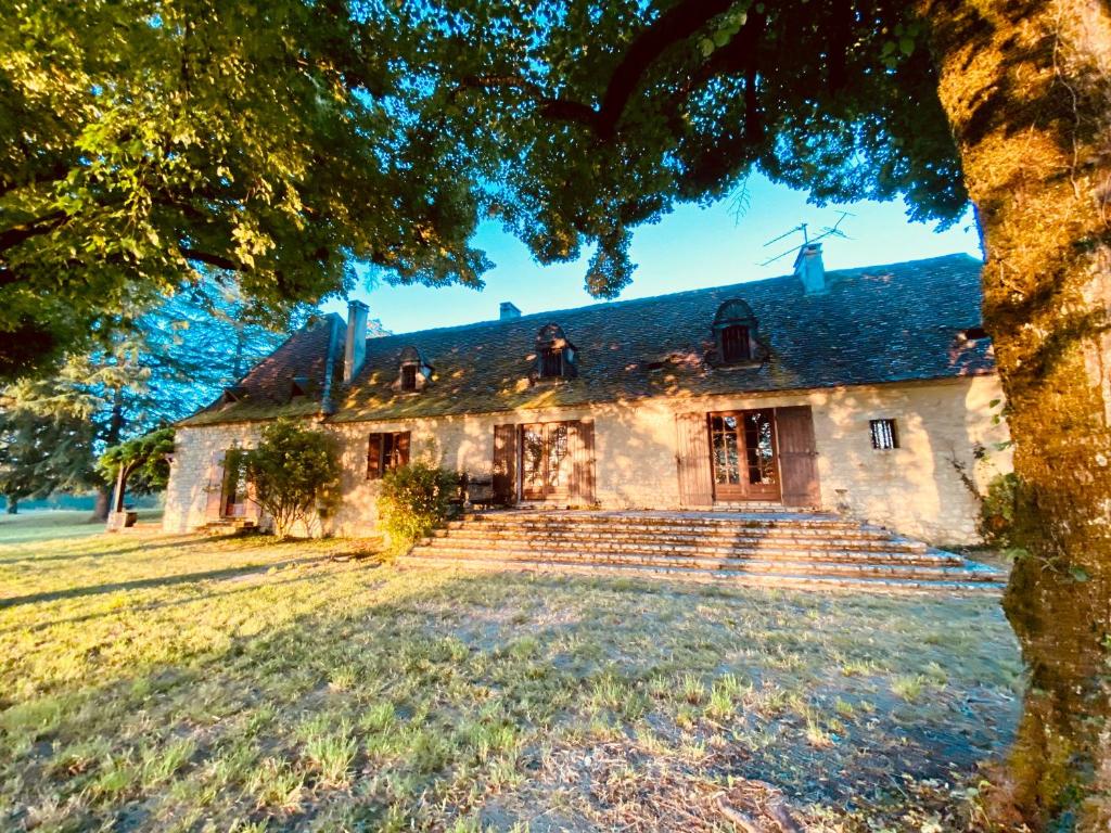 an old stone house with stairs and a windmill at Manoir du Suquet in Bardou