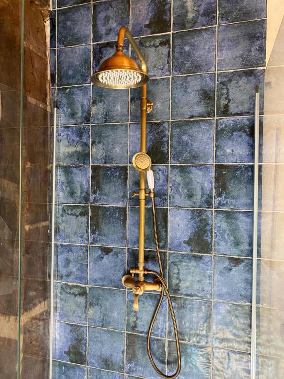 a shower with a hose attached to a tiled wall at Manoir du Suquet in Bardou