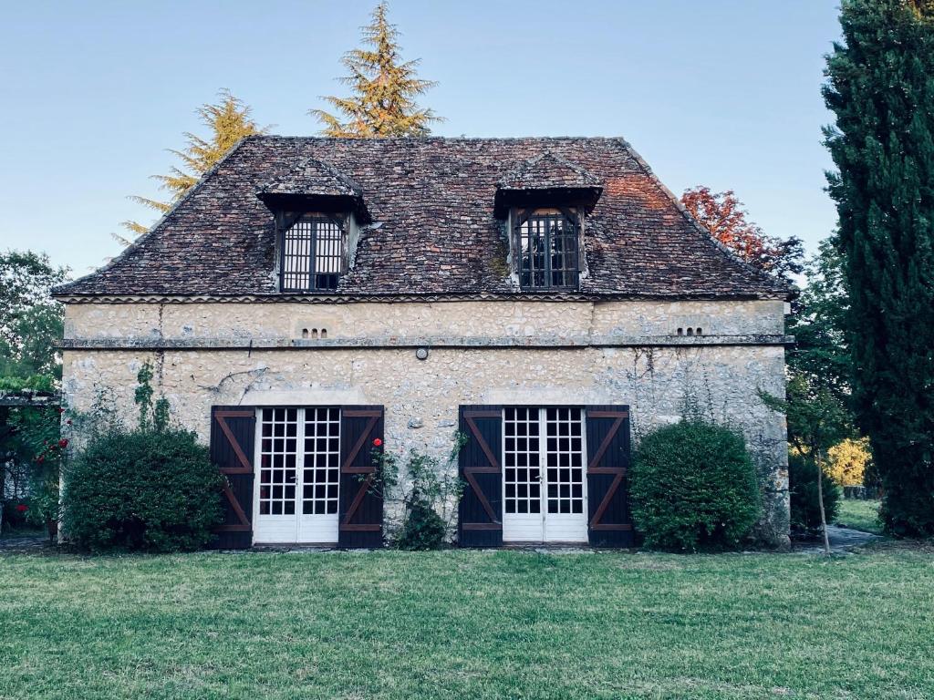 an old stone house with two windows on a field at Manoir du Suquet in Bardou