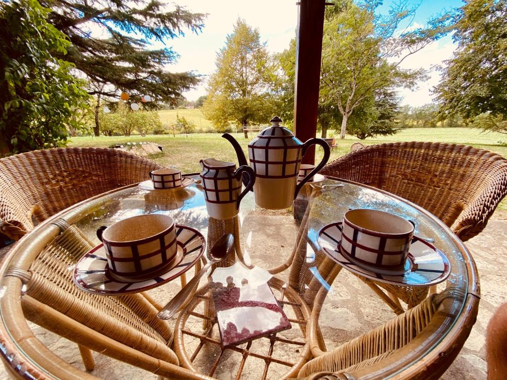 a glass table with four tea cups on top of it at Manoir du Suquet in Bardou